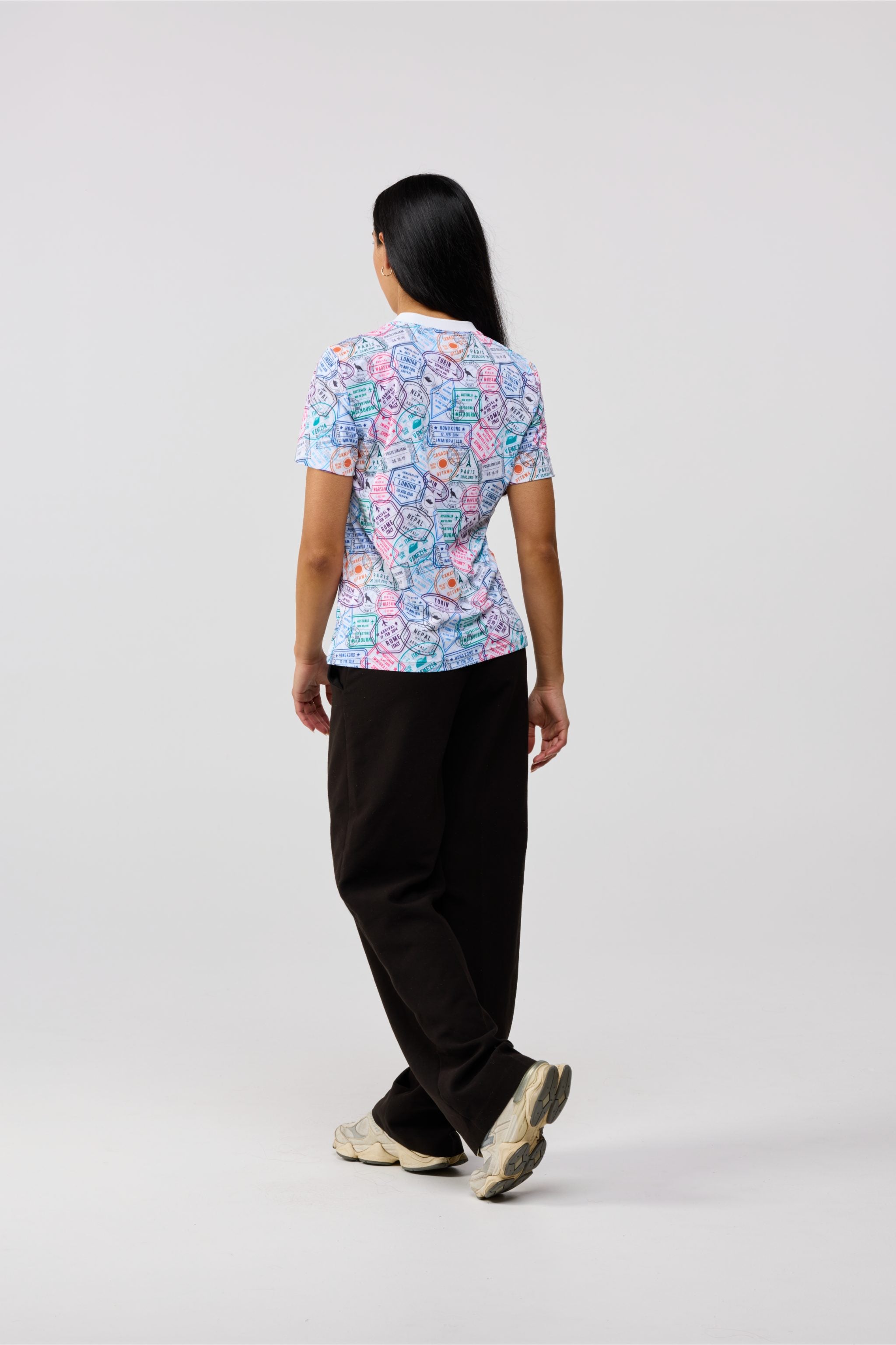 Person wearing a colorful patterned shirt and black pants on a white background