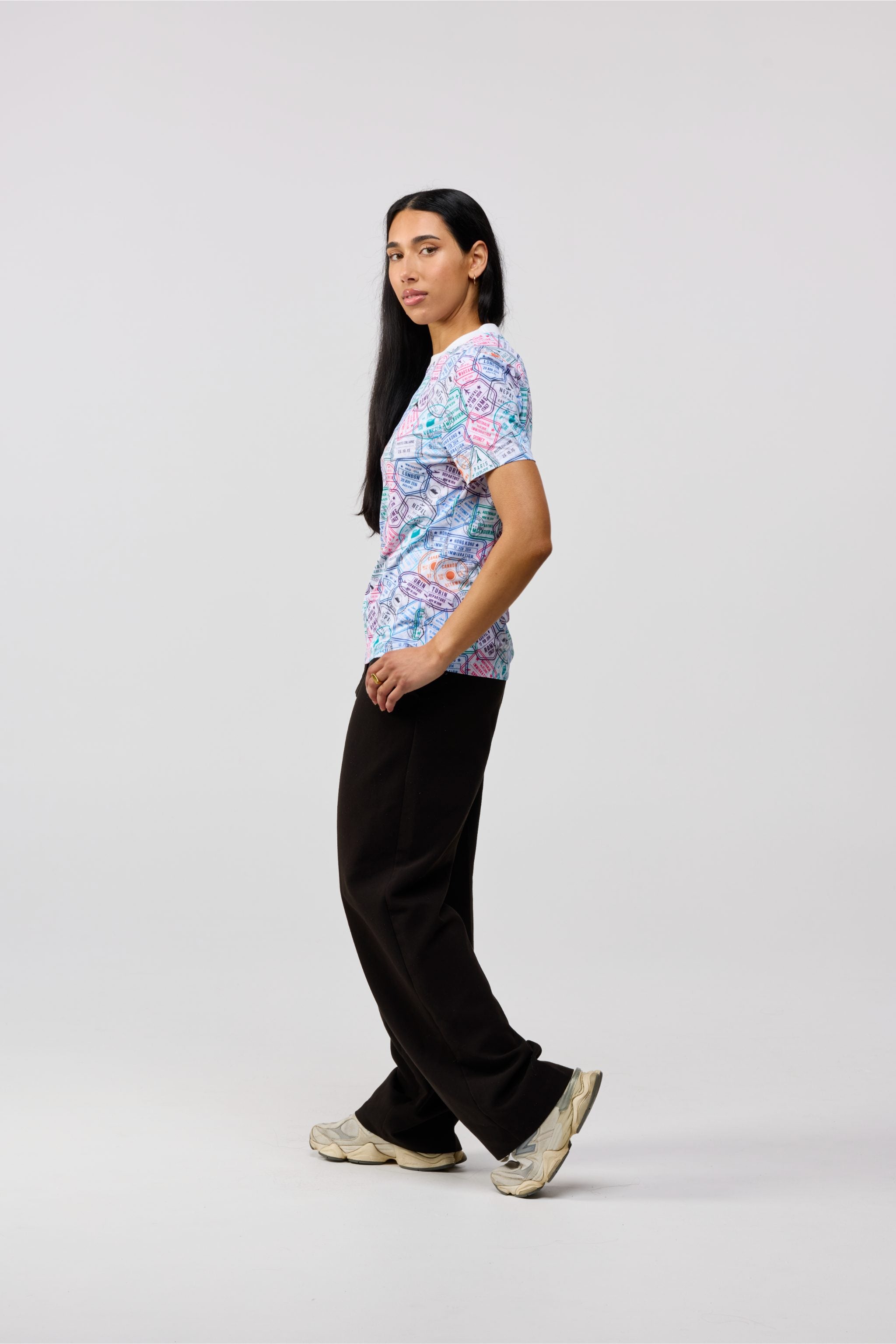 Women wearing Travel Stamp short sleeve crewneck shirt walking outdoors, showcasing movement and comfort.