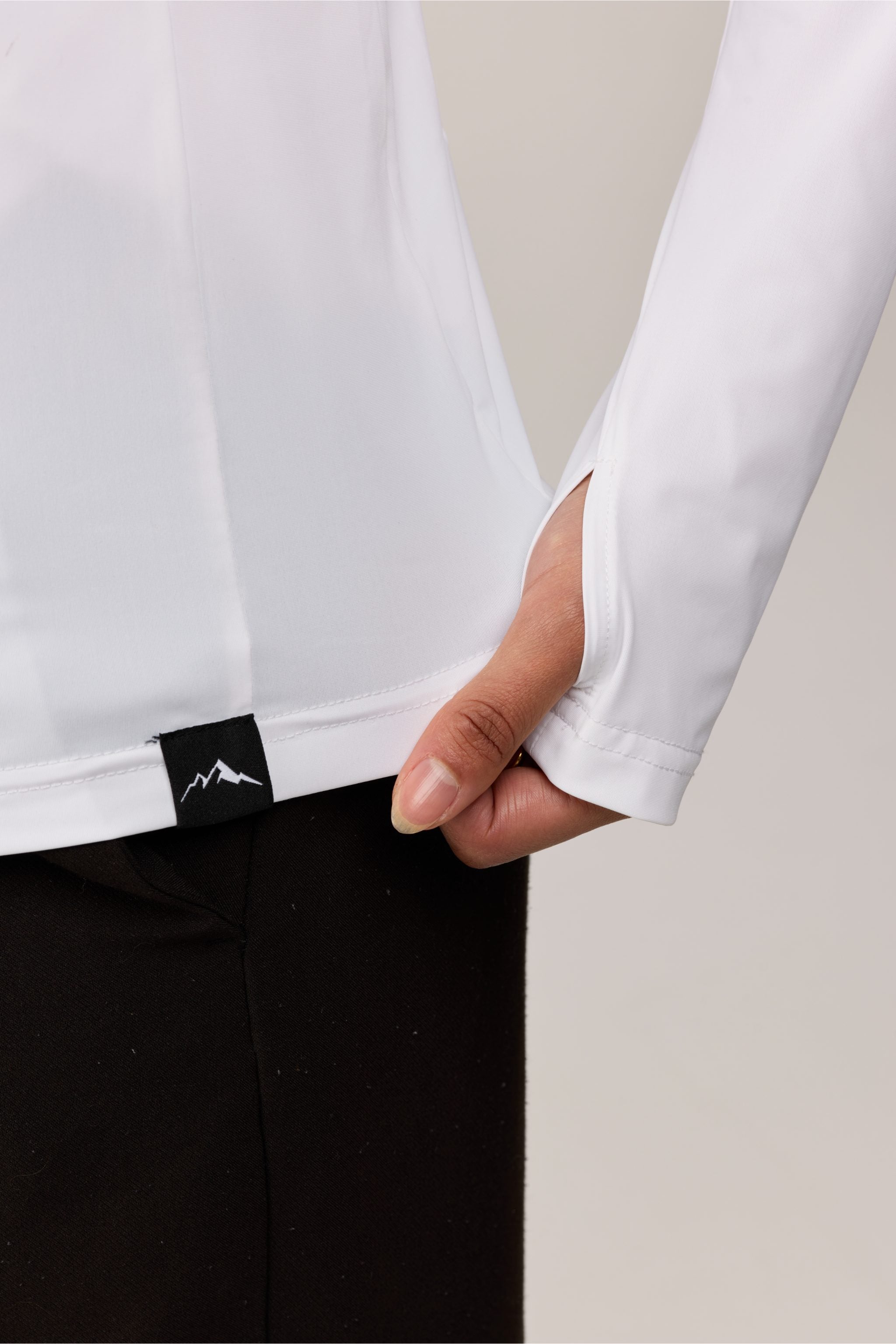 Close-up of a white long-sleeve shirt with a black label on a neutral background