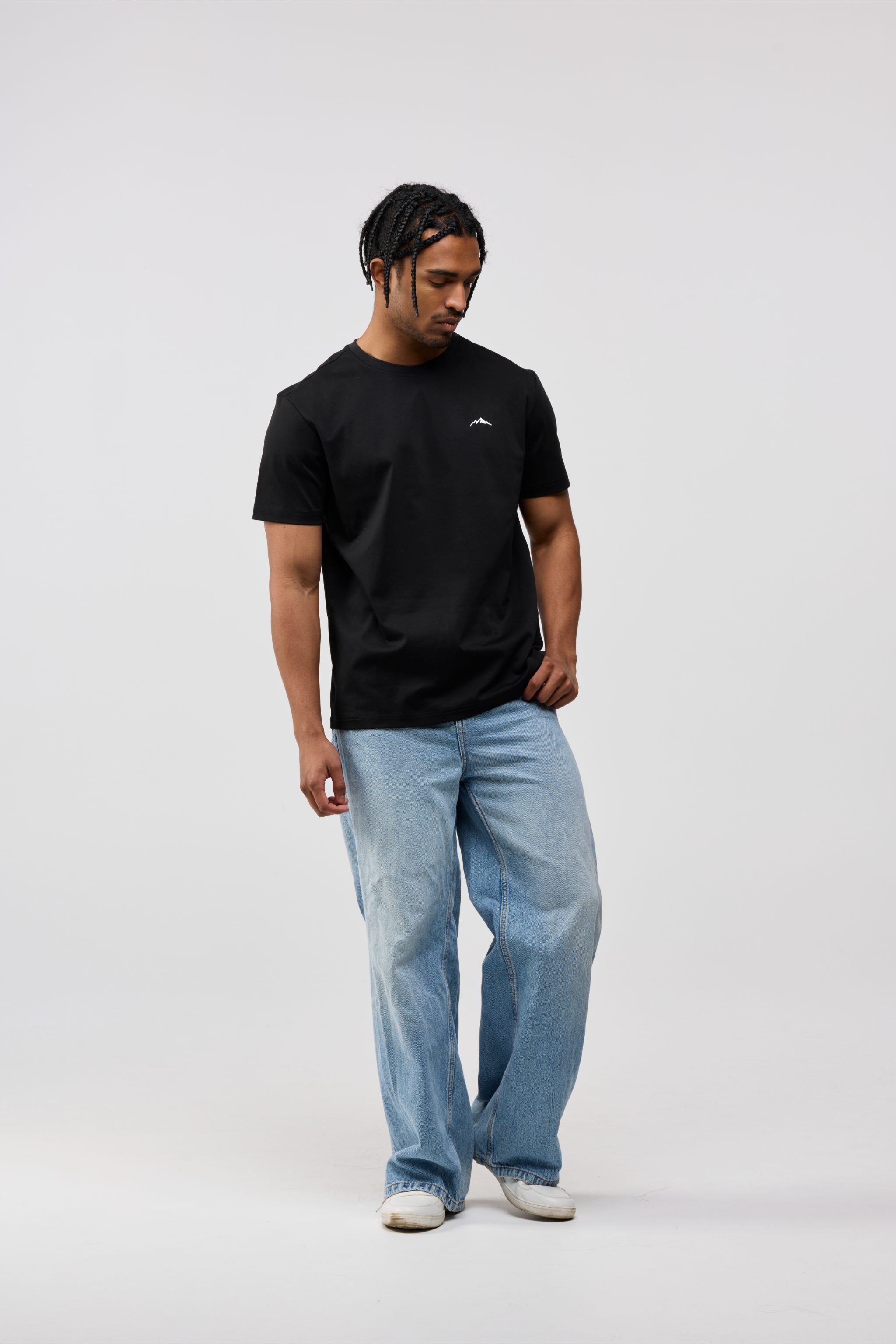Person wearing a black t-shirt and light blue jeans on a white background