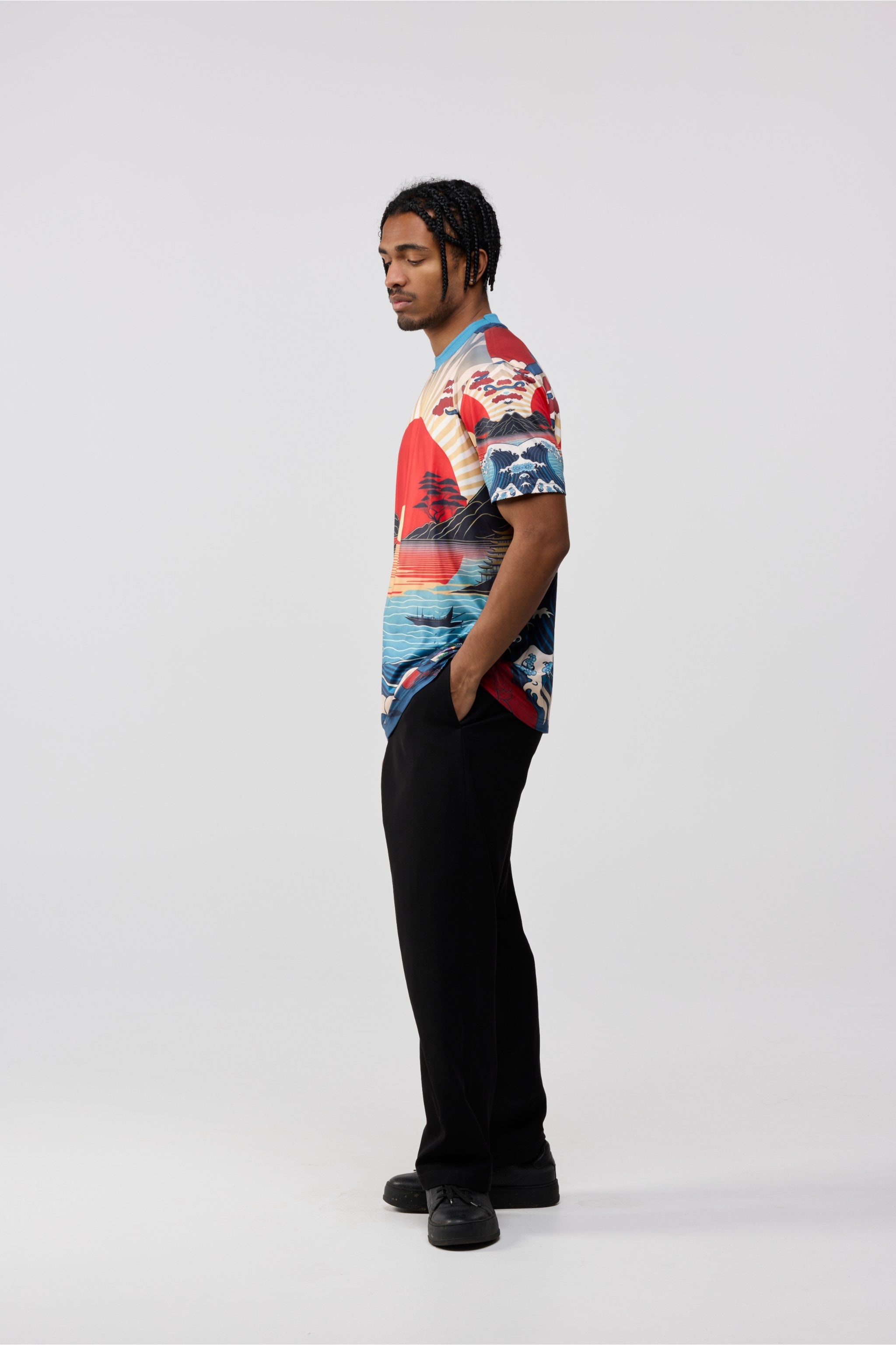 Person wearing a colorful patterned shirt and black pants on a white background