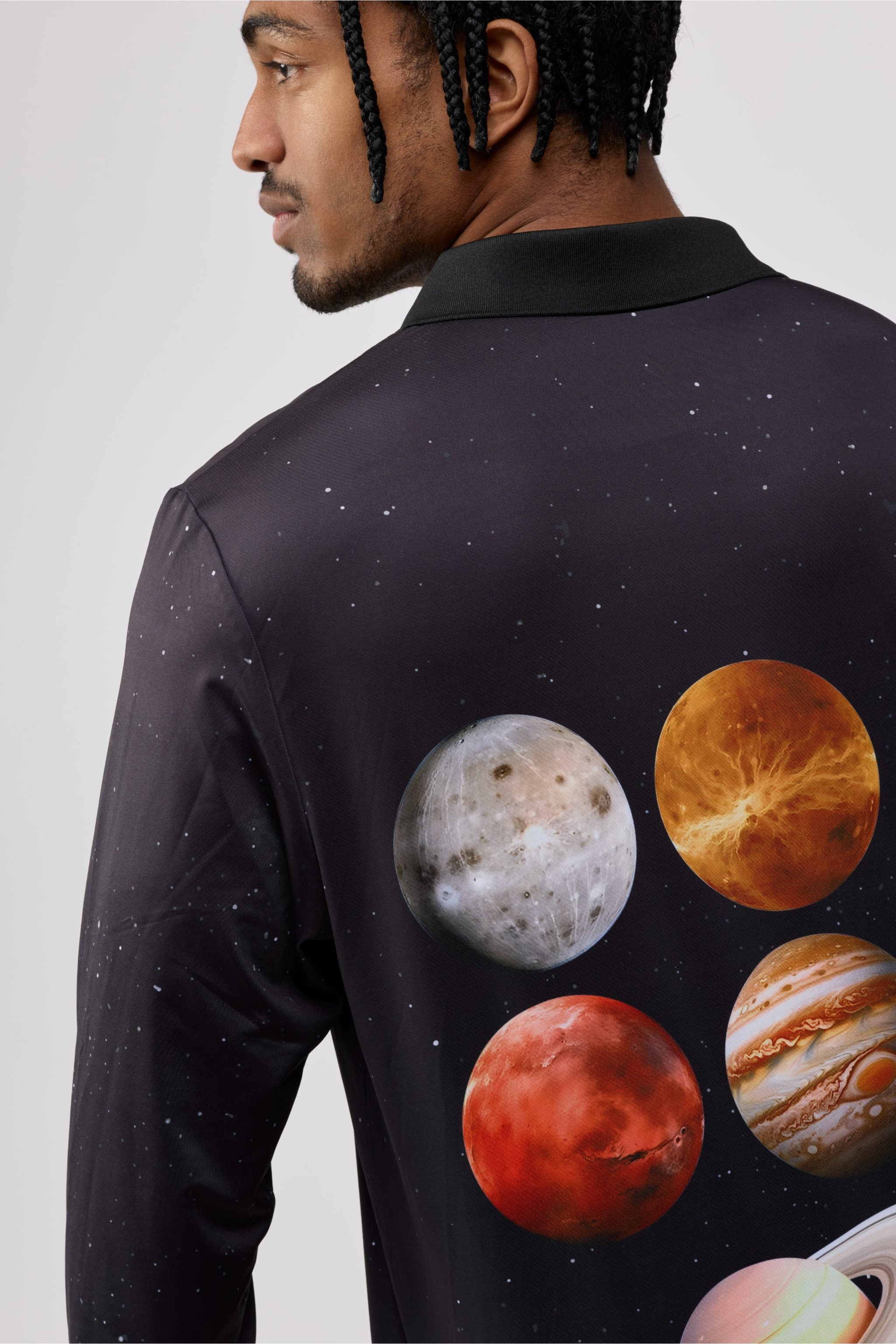 Person wearing a black shirt with planet illustrations on the back against a light gray background