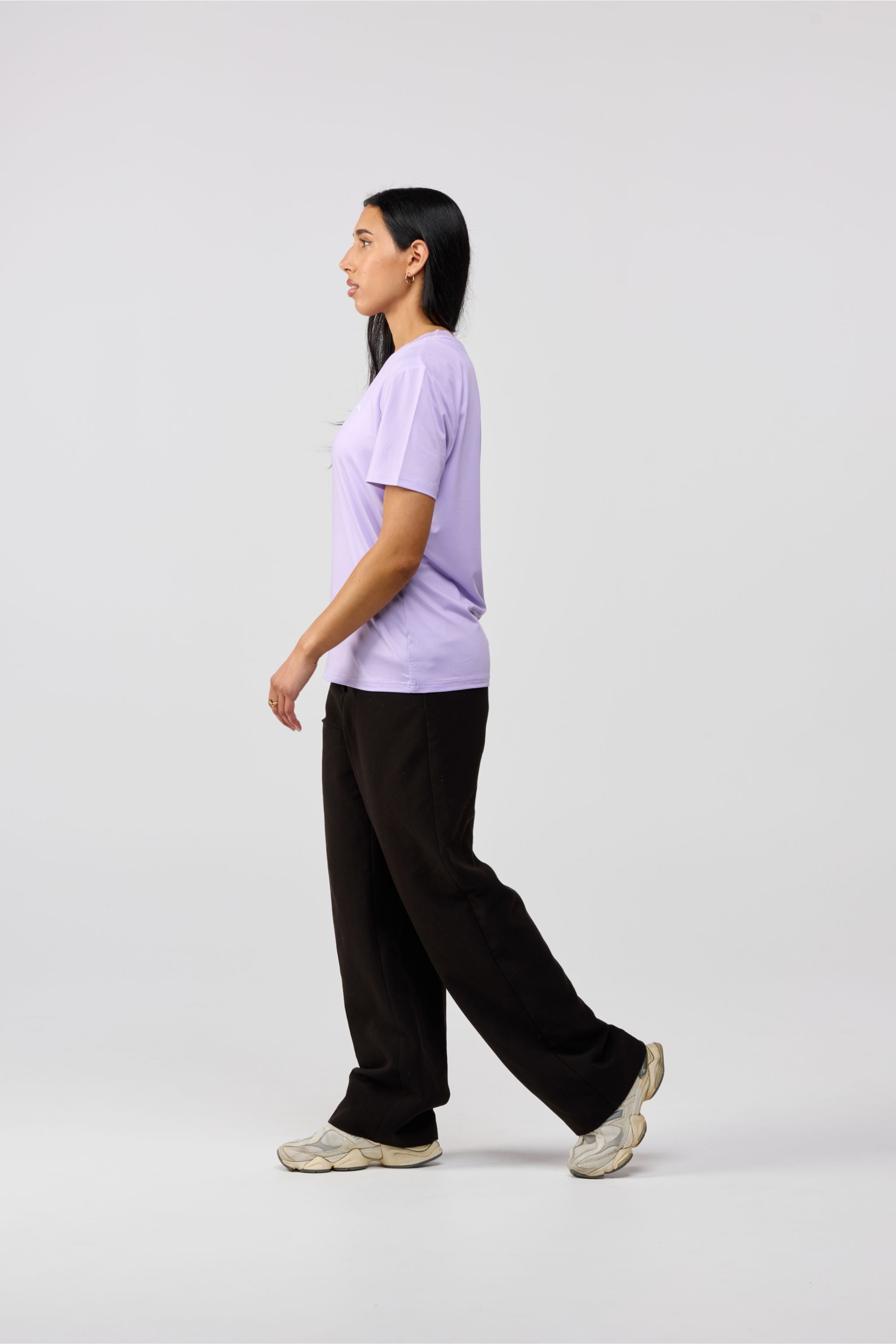 Person wearing a light purple t-shirt and black pants on a white background
