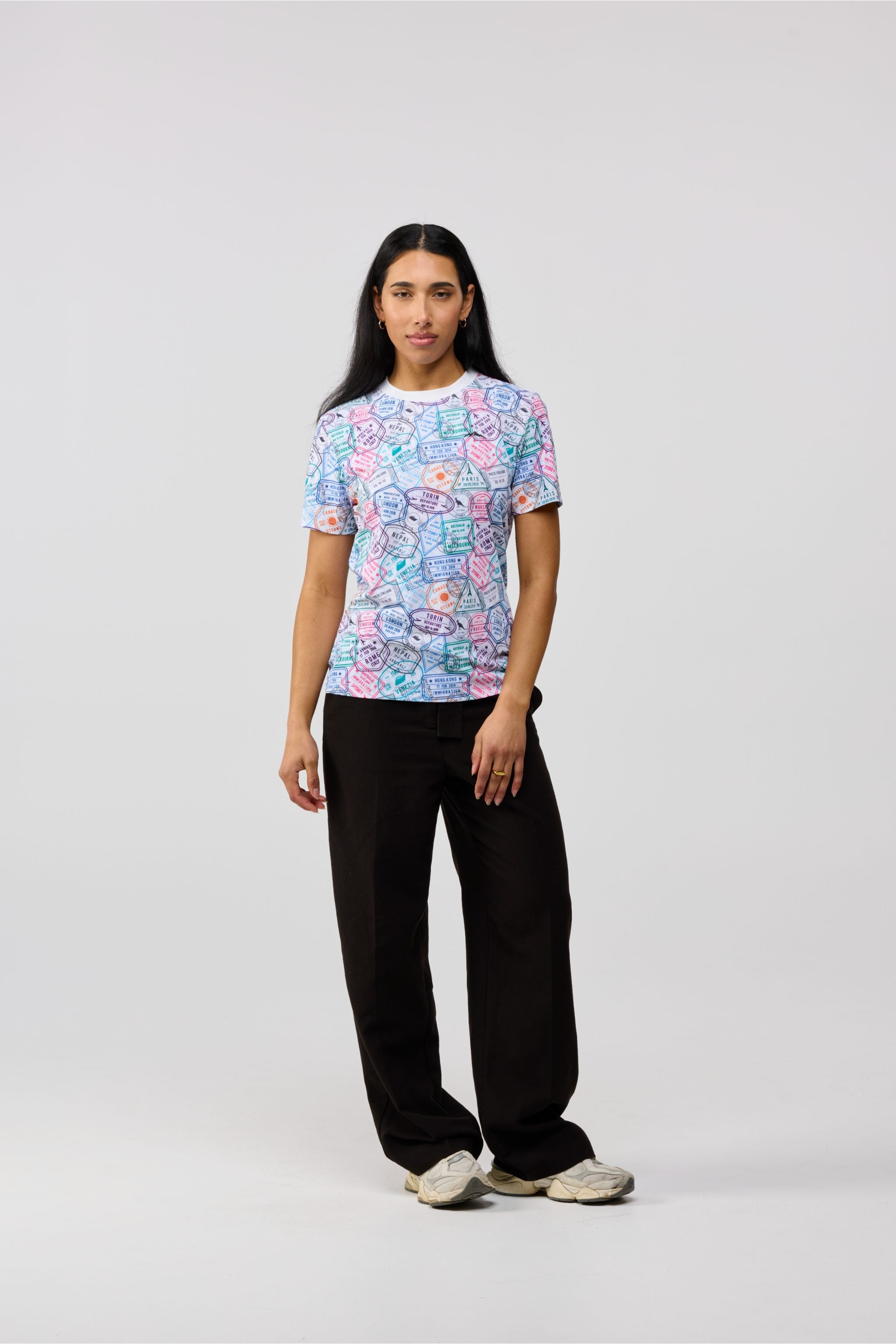 Front view of women’s Travel Stamp short sleeve crewneck shirt with vibrant passport-style prints from Paris to Hong Kong on breathable UPF 50+ fabric.